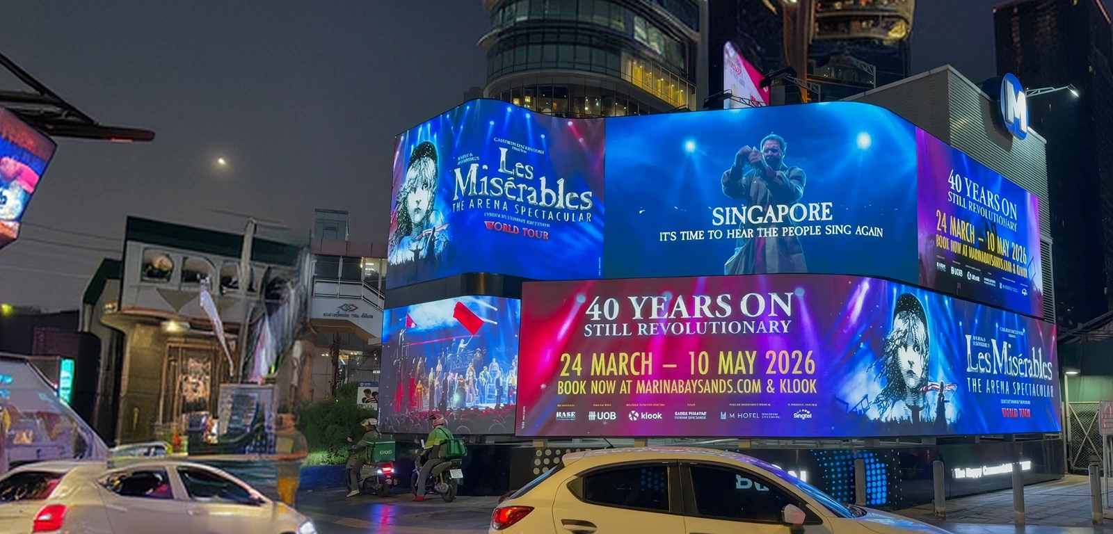 Les Misérables 40th anniversary ads on wraparound LED billboards in Bangkok at night